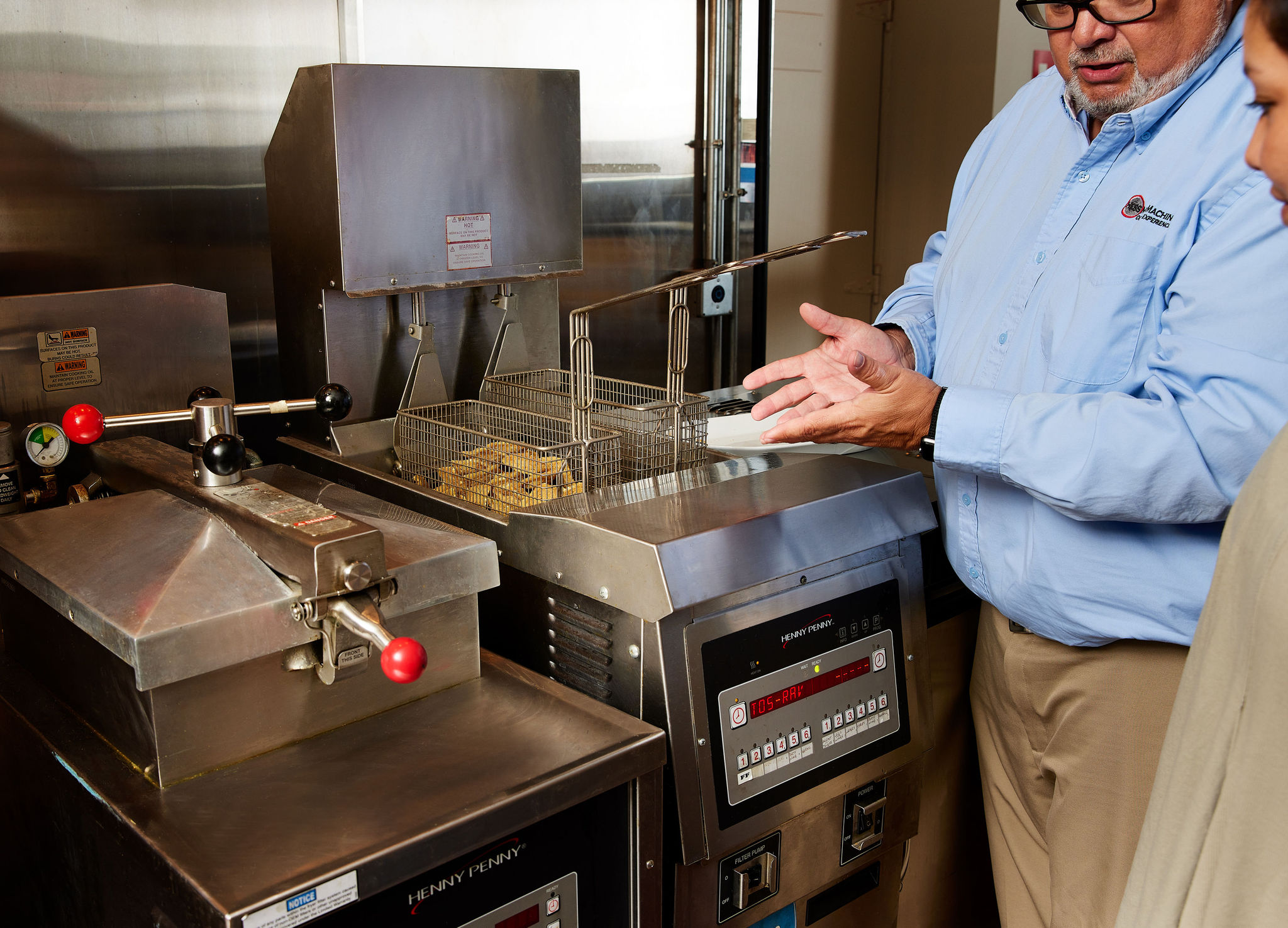 Man showing woman how to use Hess Meat Machines' frying machine